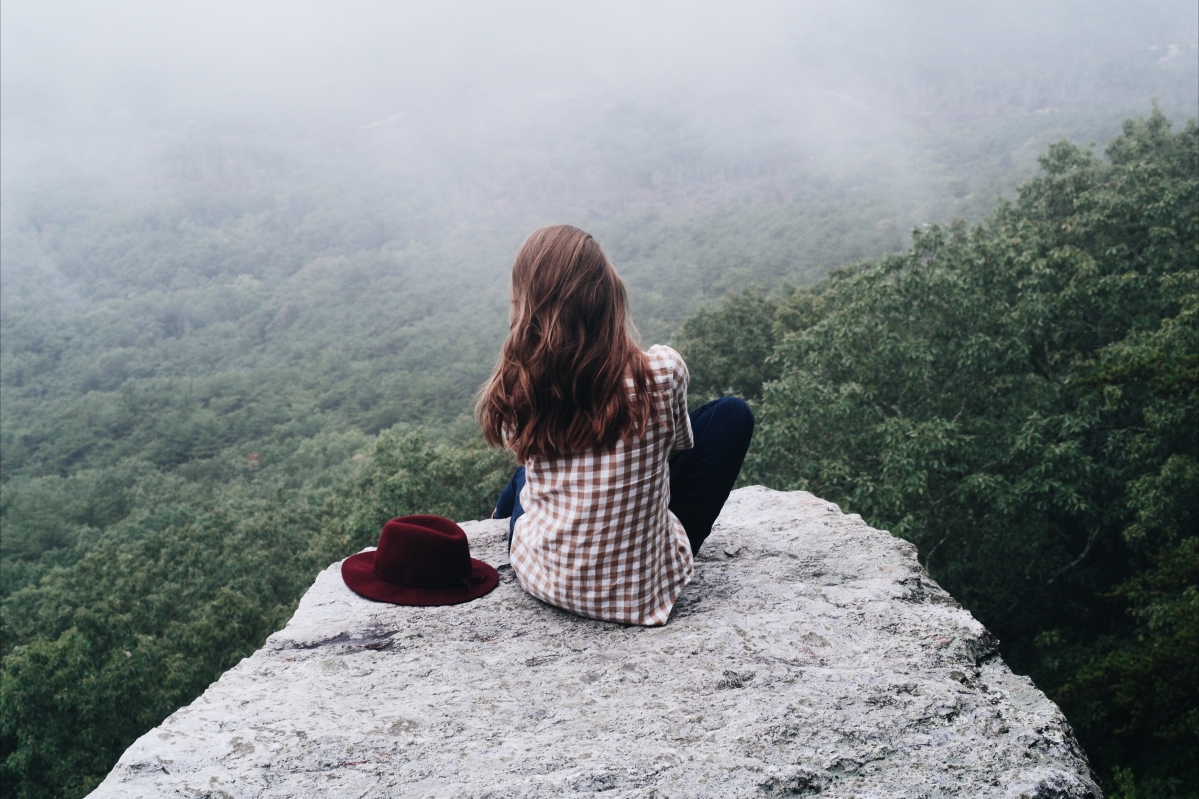 Photo of beautiful woman sitting on the top of the mountain