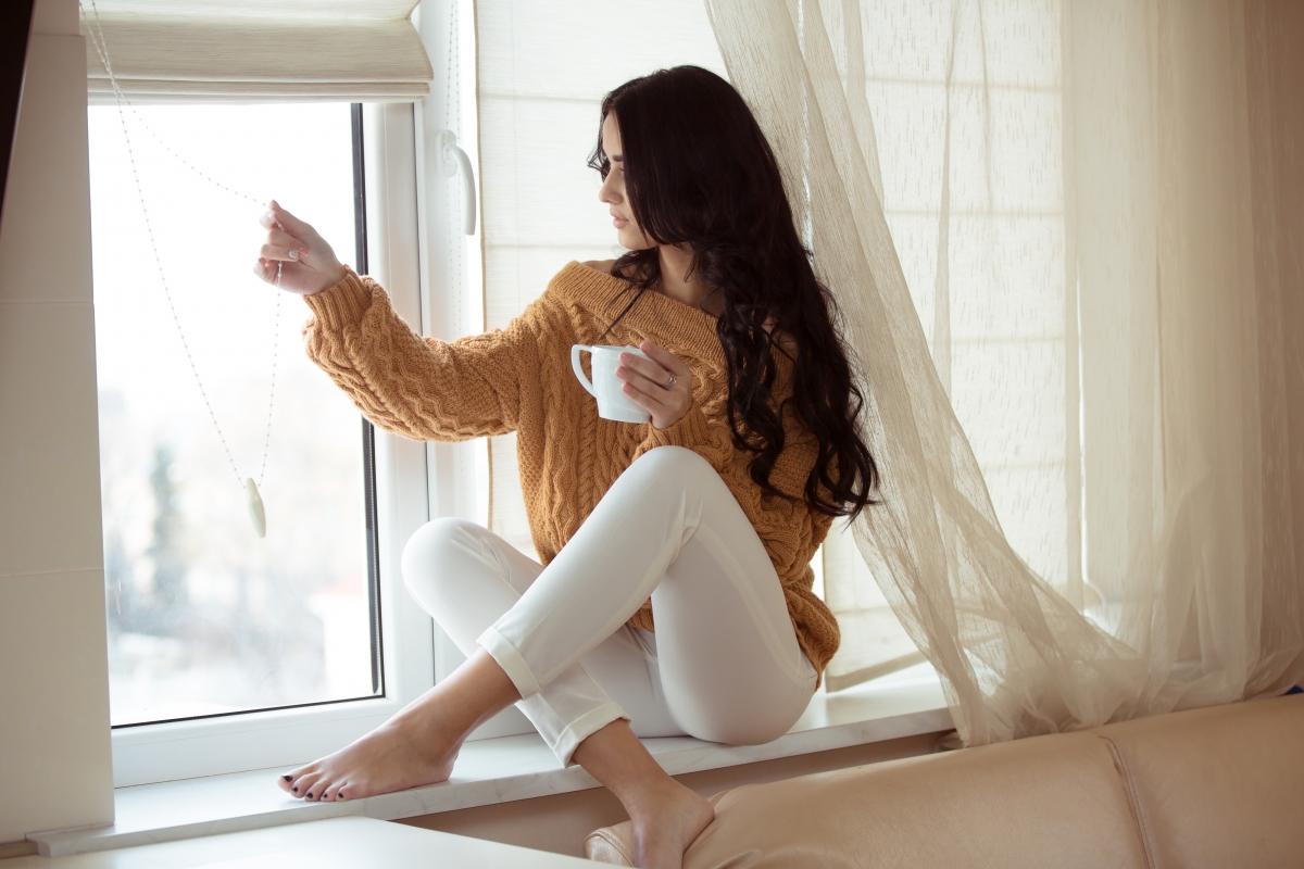 Beautiful woman sitting on the windowsill drinking coffee 4k