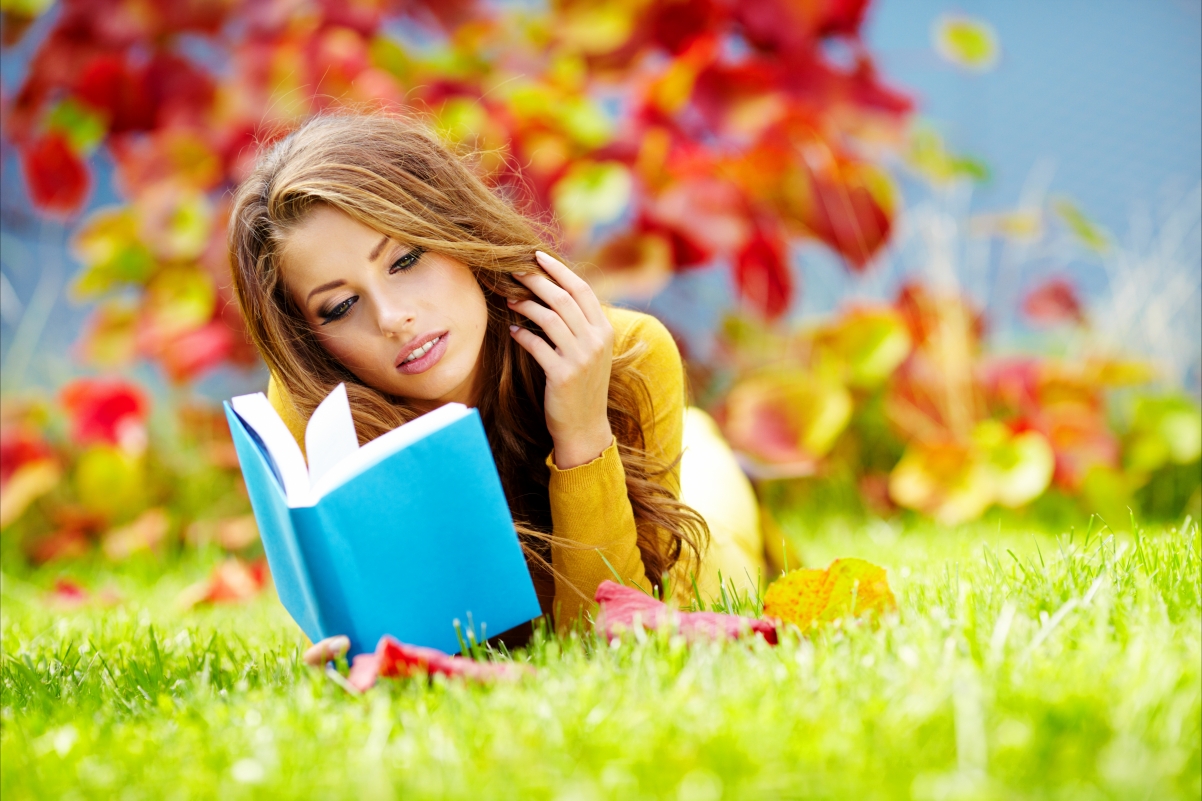 Brown-haired girl reading a book grassland 5K