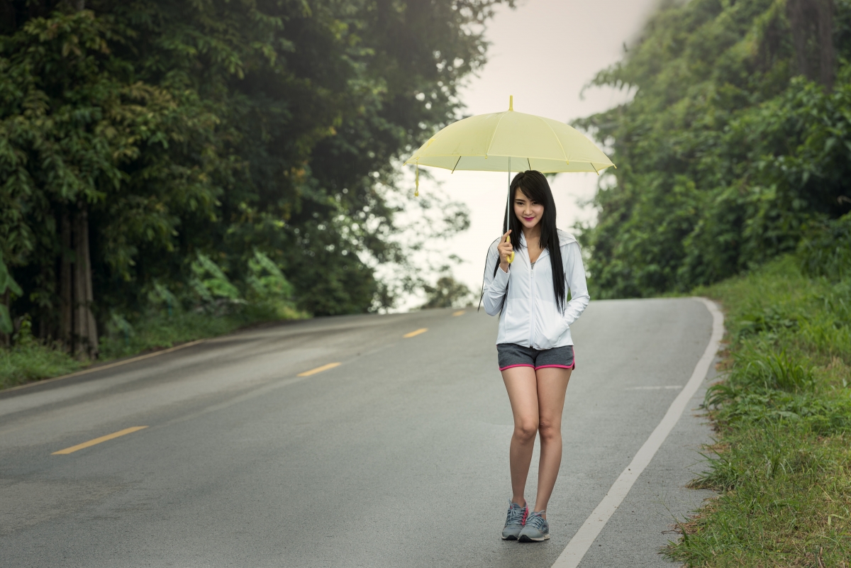 Cute woman with umbrella autumn road
