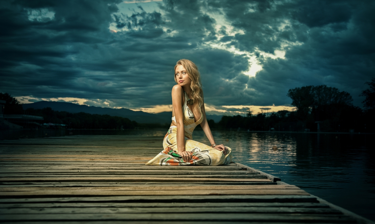Beautiful blonde sexy woman on the pier by the lake