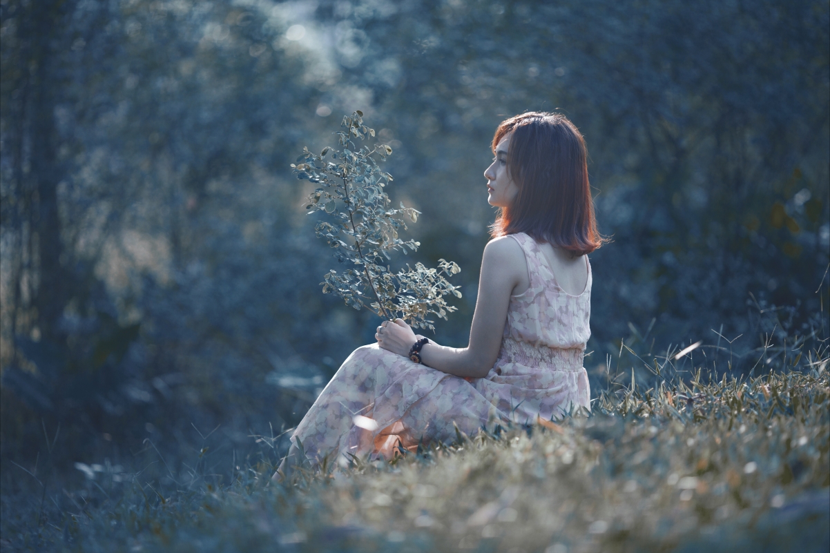 Beautiful woman sitting outdoors on the grass 5k