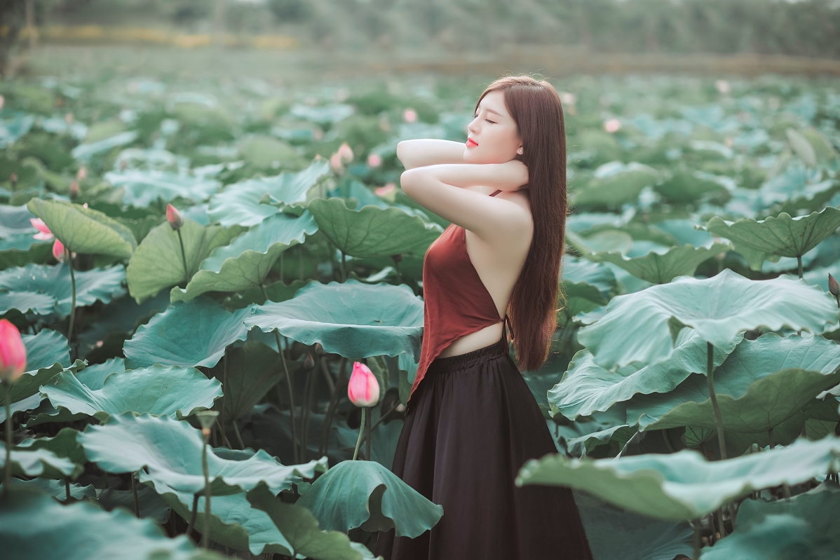 Beautiful woman with long hair and belly in lotus pond with closed eyes