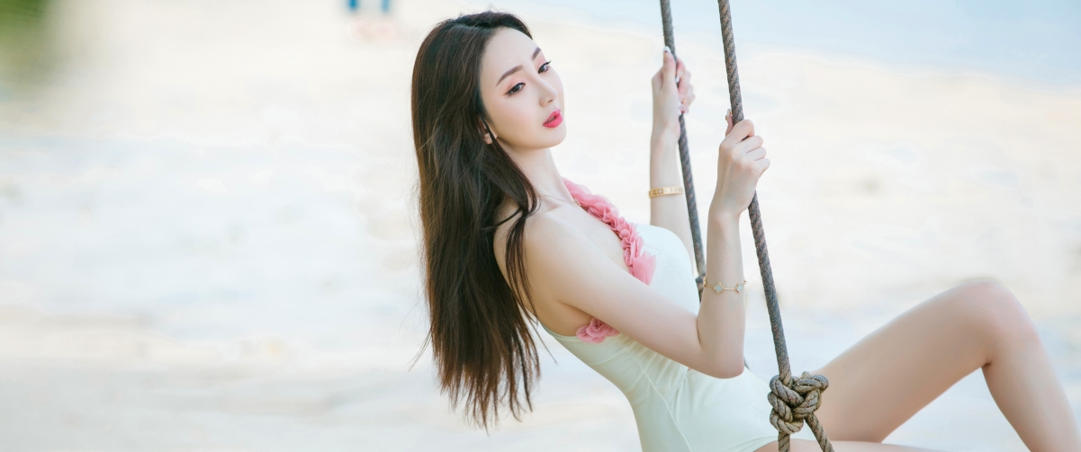 Beautiful girl on a swing by the beach