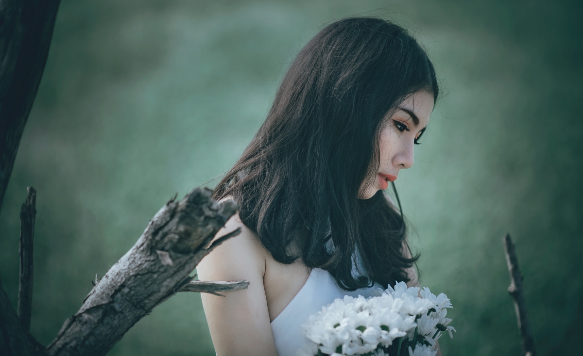 Beautiful woman in white dress holding white petals