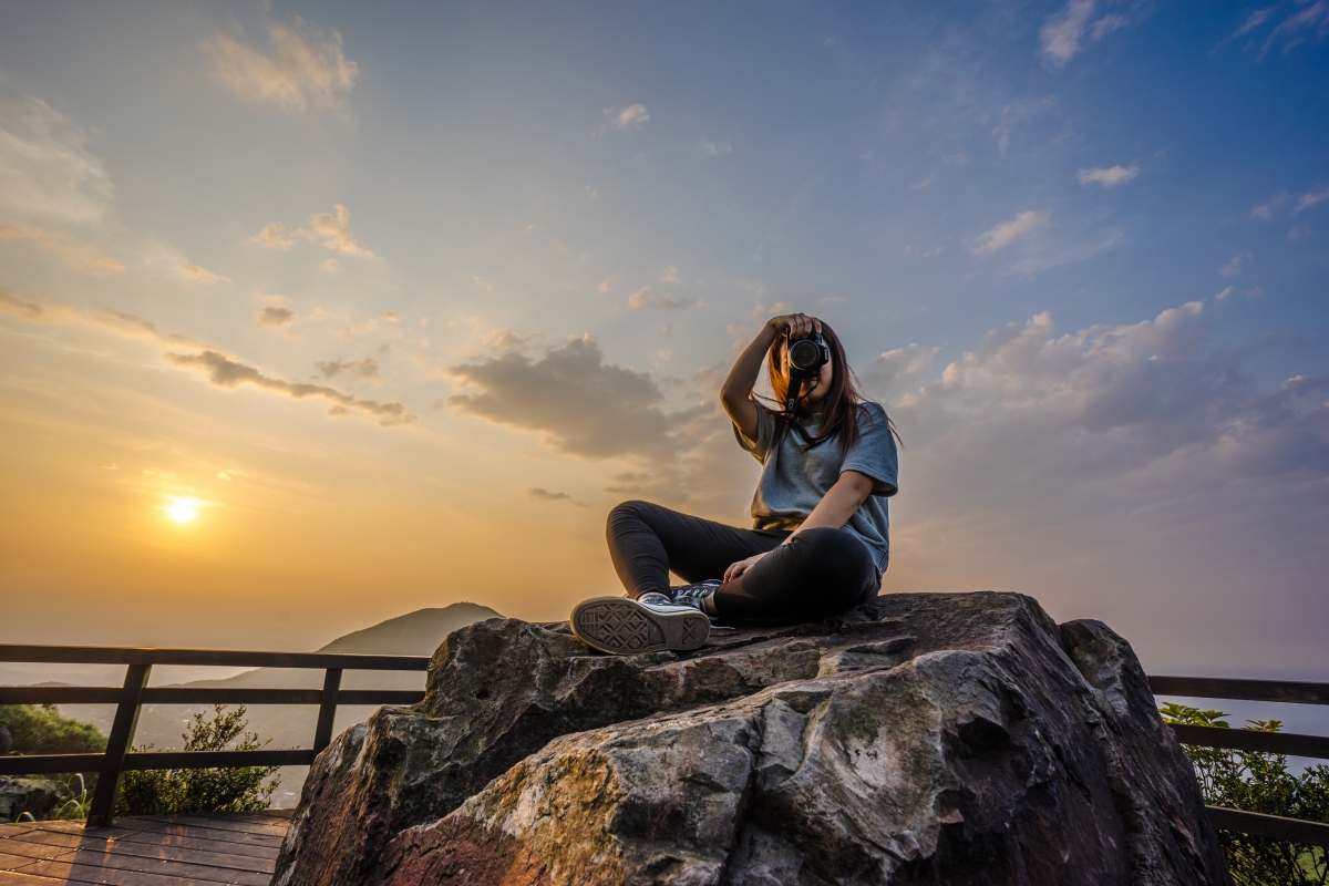 Girl sitting on the rock taking pictures 4k