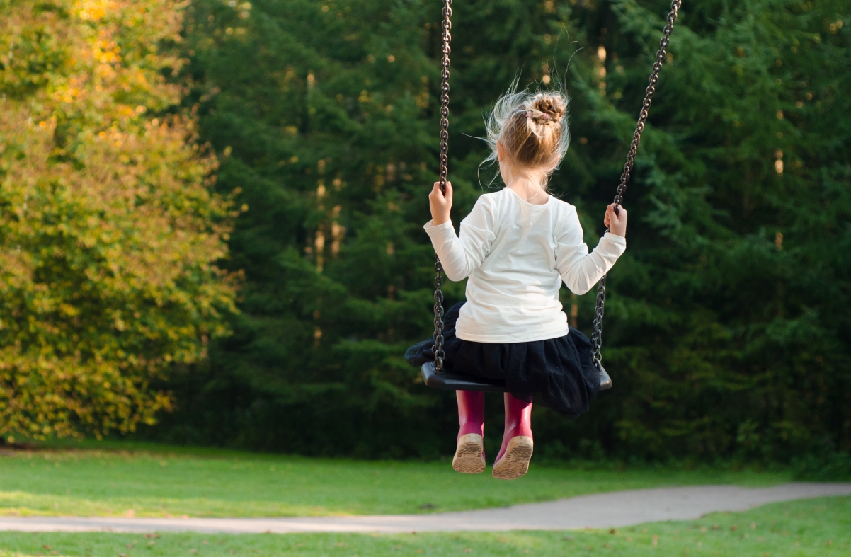 Little girl swinging on a swing alone