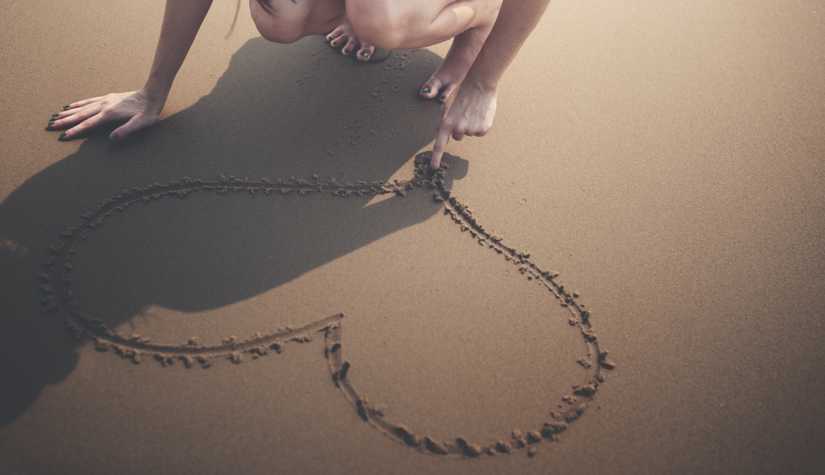 Heart-shaped drawing of a beautiful woman on the beach 5k