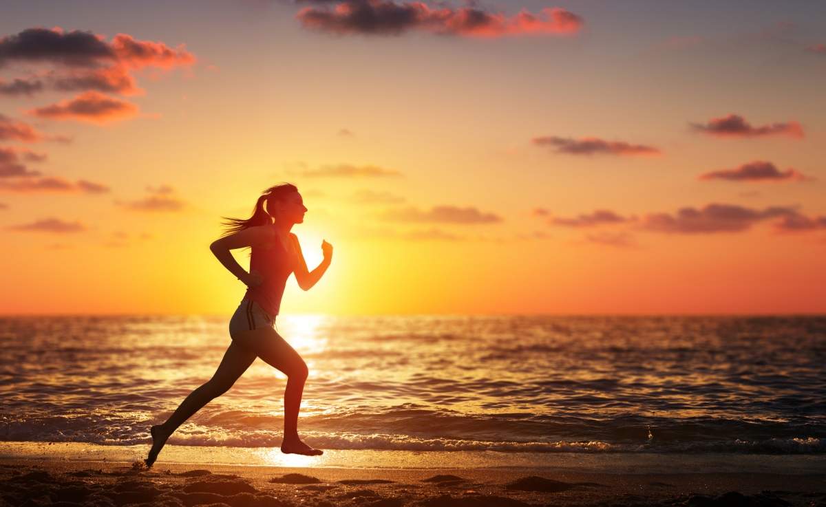 Woman running on the beach at sunset