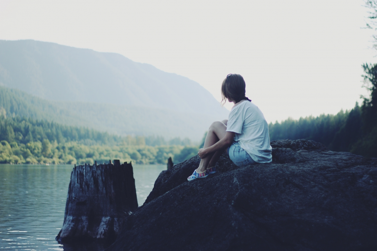 Girl on the shore of the rocky water forest