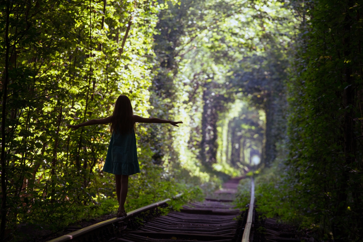 Green trees train track girl