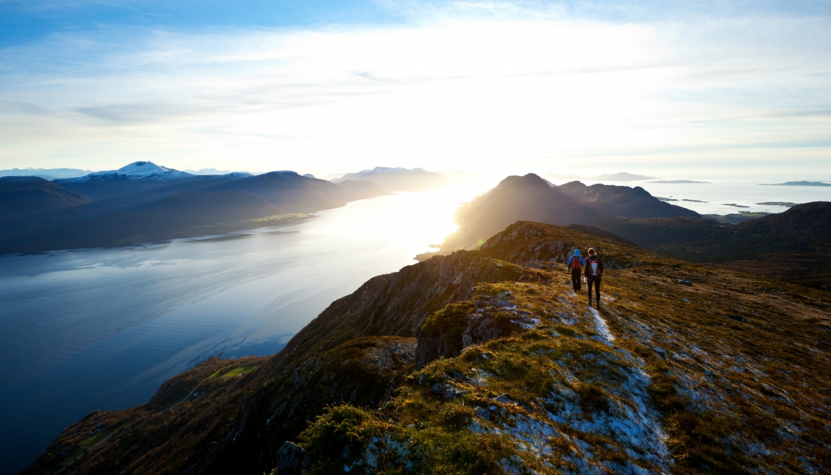 Back view of man walking on sunny mountain passerby