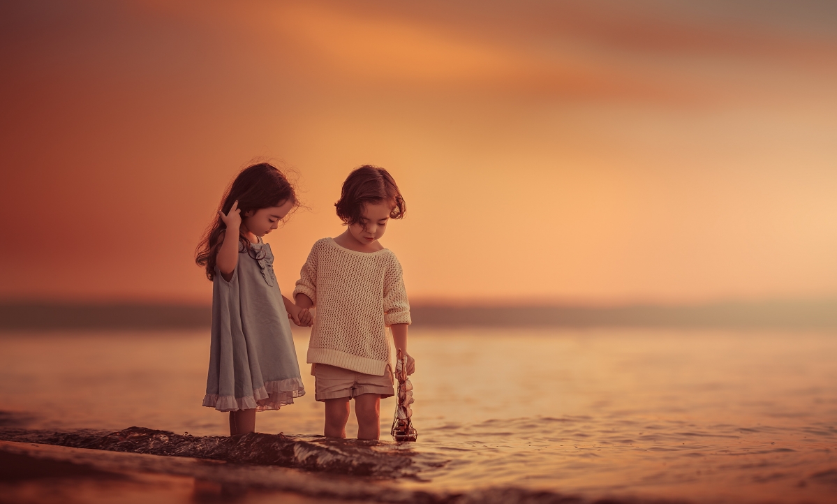 Two little kids on the beach holding hands 4K