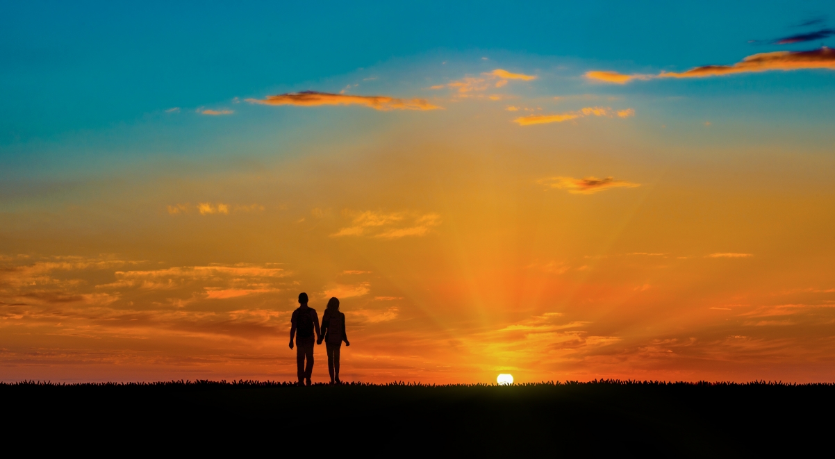 Couple holding hands at the end of the world at sunset